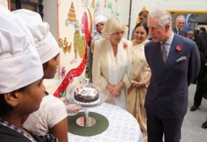 DELHI, INDIA - NOVEMBER 08: Camilla, Duchess of Cornwall looks on as Prince Charles, Prince of Wales is presented with a 65th birthday cake during a visit to Katha Community School during day 3 of an official visit to India on November 8, 2013 in Delhi, India. This will be the Royal couple's third official visit to India together and their most extensive yet, which will see them spending nine days in India and afterwards visiting Sri Lanka in order to attend the 2013 Commonwealth Heads of Government Meeting. (Photo by Chris Jackson/Getty Images)